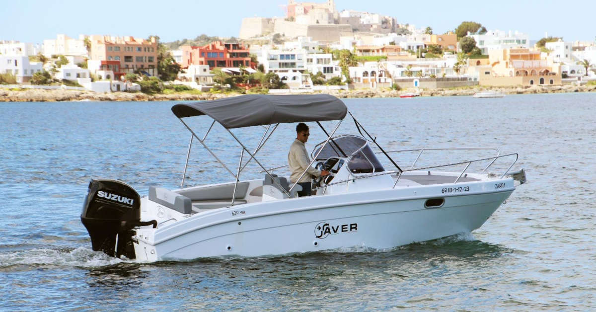 Un barco de alquiler en Ibiza navegando por la costa con Dalt Vila de fondo